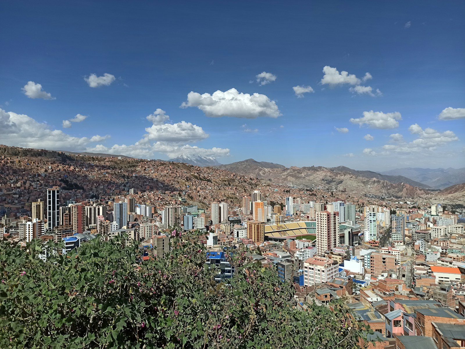 Panoramic view of La Paz at sunset with modern buildings and snow-capped mountains in the background